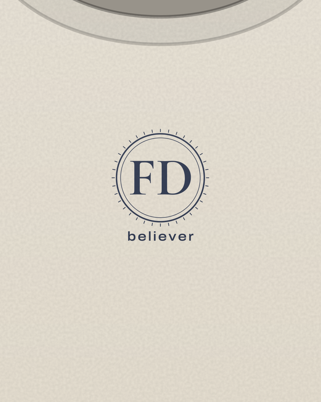 Close-up of the “FD believer” print in navy on a bone tee