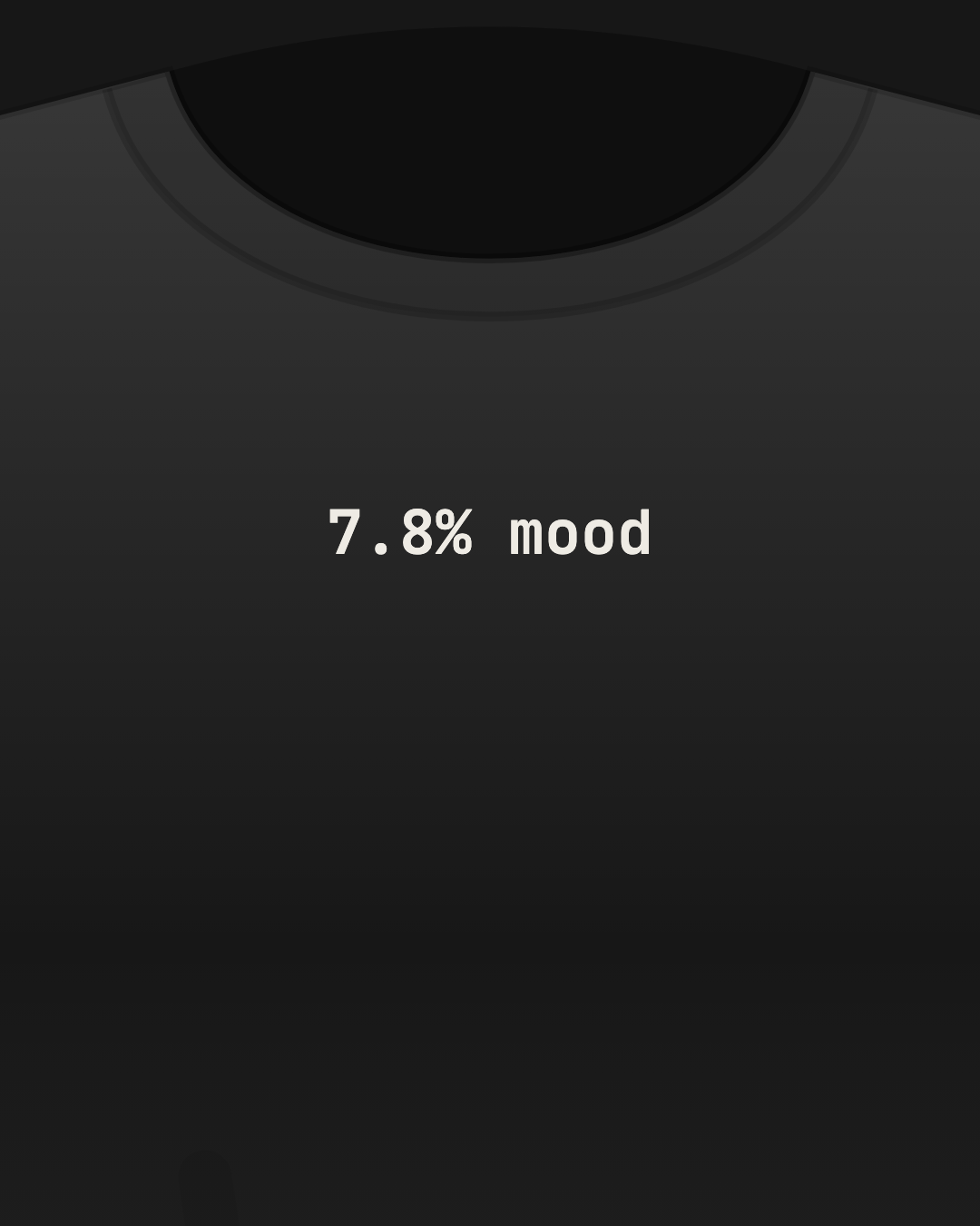 Close-up of a black tee with “7.8% mood” printed small in off-white on the chest
