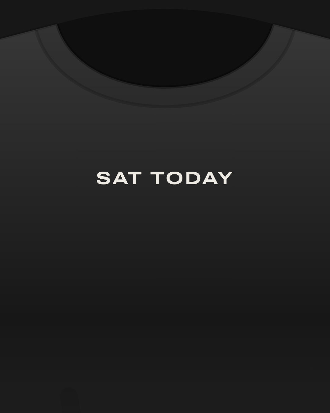 Close-up of a black tee with “sat today” printed small in off-white on the chest