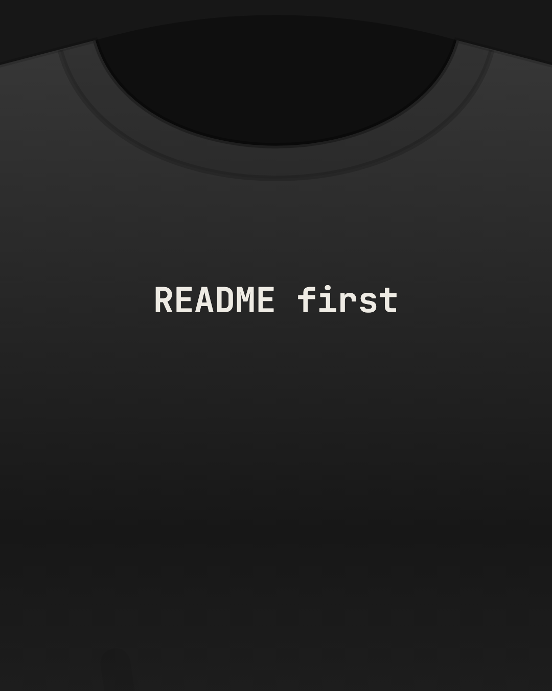 Close-up of a black tee with “README first” printed small in off-white on the chest