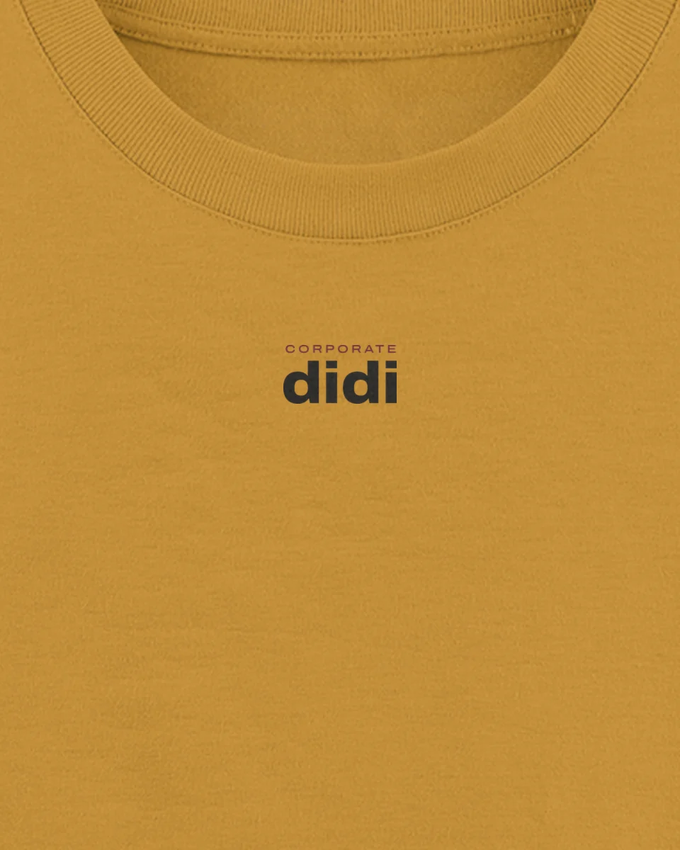 Mockup: close-up of “Corporate didi” printed on a mustard oversized tee